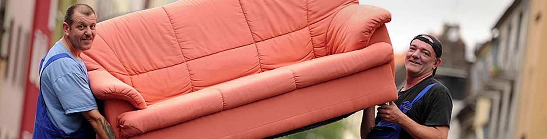 Zwei Männer tragen ein rotes Sofa