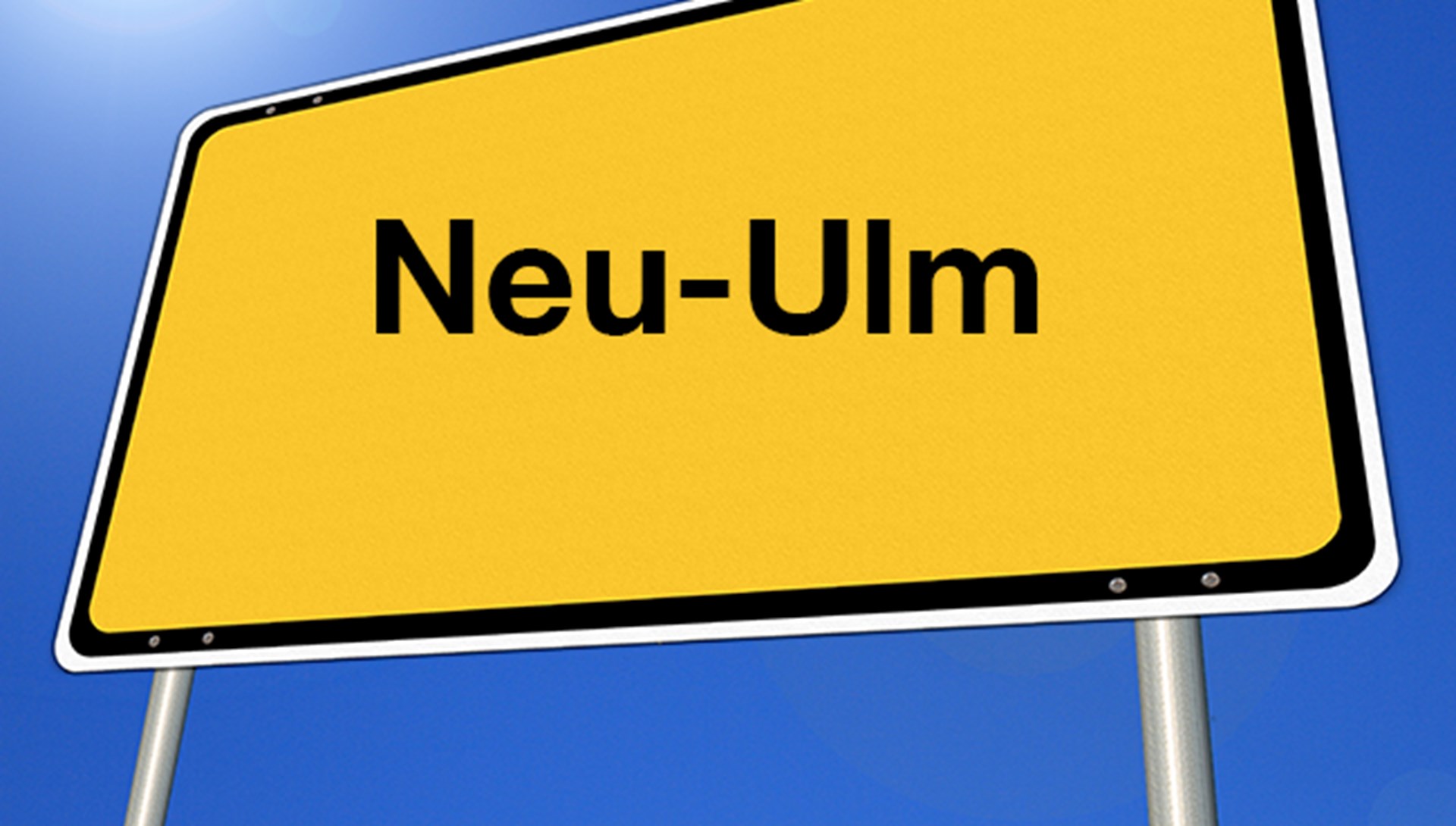 Das Foto zeigt ein schräg verzerrtes gelbes Ortsschild mit der Aufschrift Neu-Ulm.
