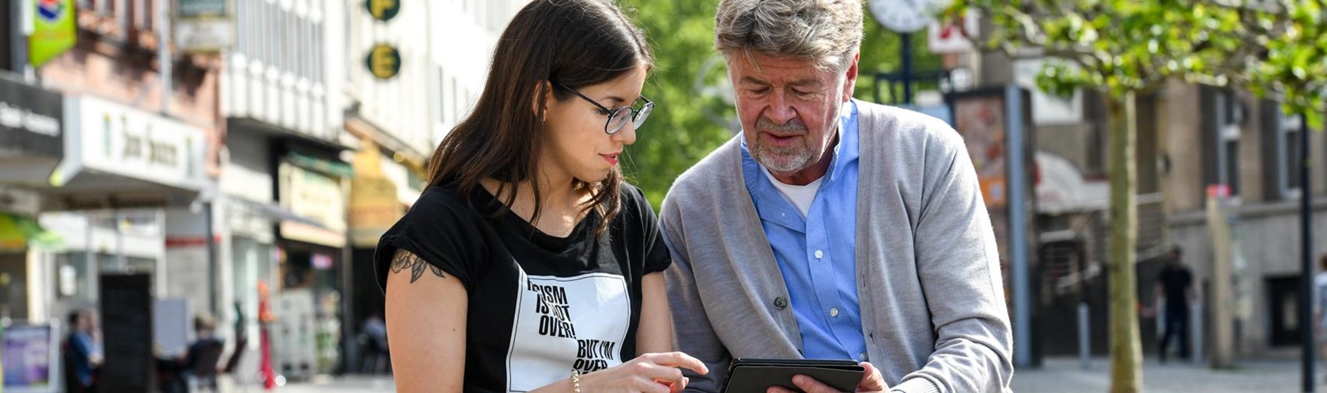 Eine junge Freiwillige zeigt einem älteren Herrn den Umgang mit dem Smartphone